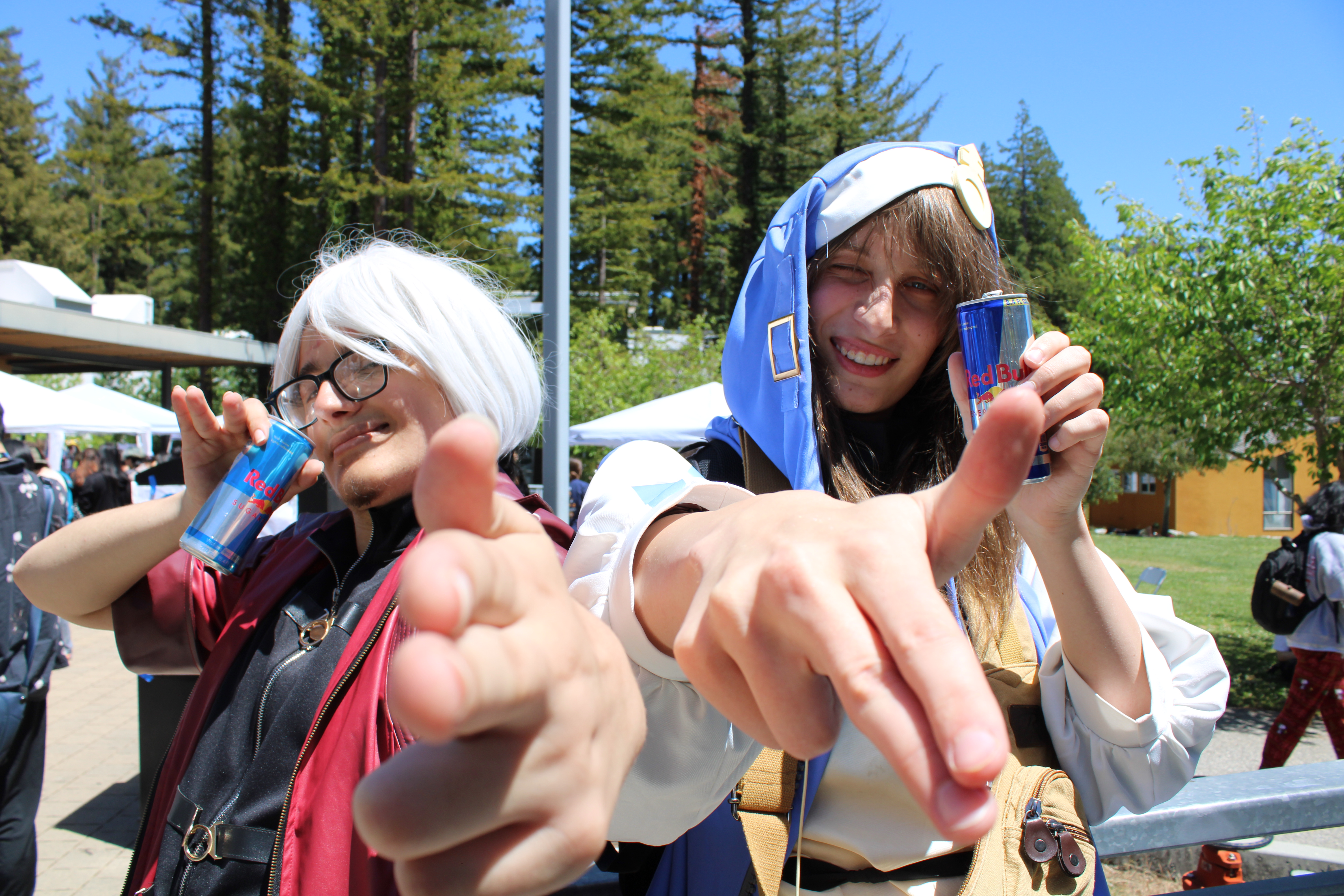 two people in cosplay posing with cans of redbull